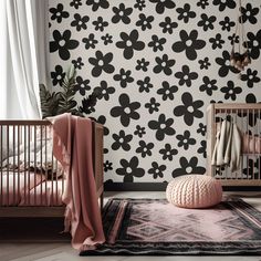 a baby's room with black and white flowers on the wall, pink bedding and rug