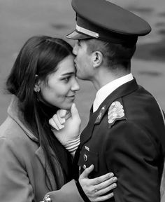 a man in uniform kissing a woman on the cheek