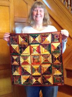 a woman is holding up a quilt on the stairs