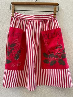 a red and white striped skirt hanging up on a hanger with the words happy holidays printed on it