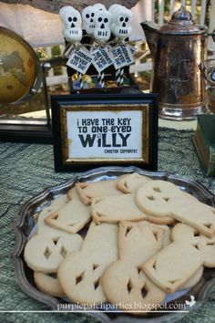 there is a plate full of cookies on the table with skeleton decorations and skulls in the background