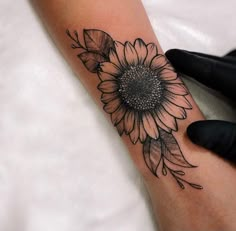 a woman's arm with a sunflower tattoo on it