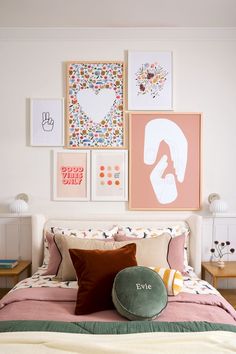 a bedroom with pictures on the wall above the bed and pillows in front of it