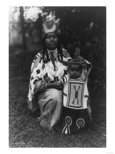 an old black and white photo of a native american woman holding a child