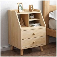 a small wooden shelf with two drawers on each side and a bed in the background