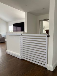 a living room with hard wood floors and a flat screen tv mounted on the wall