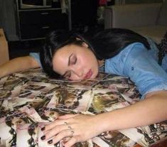 a woman laying on top of a bed covered in pictures and nails with her eyes closed