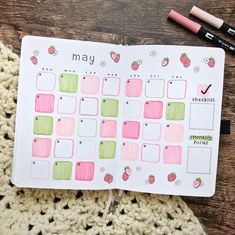 an open planner with strawberries on it next to some crochet and markers