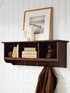 a shelf that has some books on it and a coat rack with two coats hanging from it