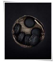 black macaroons in a basket on a dark background