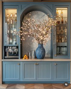 a vase filled with flowers sitting on top of a wooden shelf next to a bar