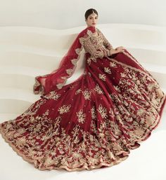 a woman in a red and gold gown poses for the camera with her hands on her hips