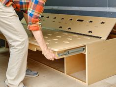 a man is bending over to look at the bottom of a drawer that has holes in it