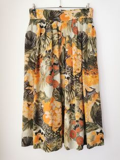 Vintage floral print midi skirt from the 90s. Women's high waist boho skirt with floral print in earthy tones - orange, olive green, brown. The skirt has elastic on the waist, closes with a zipper on the back and falls free below the knees. Material: skirt is 100% Viscose, lining is 100% Polyester Size; 38 DE, which is 8 US or M. Model shown on the photos wears 38 DE / 8 US / M. To be sure this item would fit you, please check the measurements below. Approximate Measurements ( taken when skirt lying flat, double waist and hips) Waist (double that): Stretches from 14 inches / 35.5 cm up to 16 inches / 40.6 cm  Length: 30 inches / 76.2 cm Condition: Excellent vintage condition! Has been shortened by previous owner (please refer to the last photo). This listing includes the skirt, you can see Vacation Floral Print Full Skirt Bottoms, Floral Print Full Skirt Bottoms For Vacation, Floral Print Full Skirt For Vacation, Retro Floral Print Mini Skirt, Spring Tropical Print Flowy Skirt, Retro Mini Skirt With Floral Print, Retro Floral Print Summer Skirt, Retro Floral Print Skirt For Summer, Floral Print Knee-length Bottoms For Beach