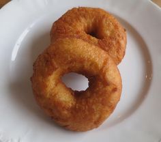 two donuts on a white plate sitting on a table