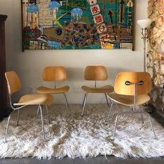 three chairs are sitting in front of a painting on the wall and rug below them