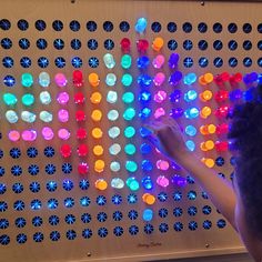 a person standing in front of a wall with colorful lights on it's sides