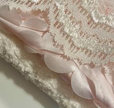 the fabric is white and has pink flowers on it, along with other laces