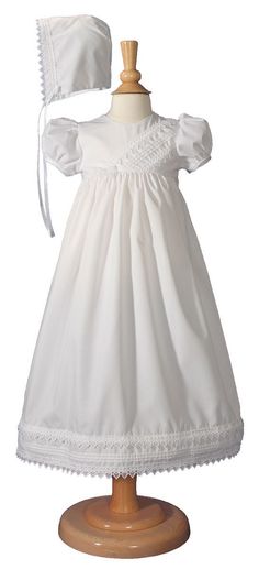 a white dress and bonnet on a mannequin headdress for a baby girl