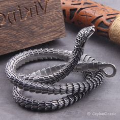 Elevate your style with this Viking Ouroboros vintage snake bracelet, a symbol of eternal cycles and timeless fashion. Crafted from high-quality stainless steel, this necklace exudes durability and style. Choose from three lengths: 50cm, 60cm, or 70cm, or opt for private custom sizing for the perfect fit. Packaged with care, each necklace comes with a black jewelry bag and a wooden box, making it an ideal gift for the fashion-forward individual in your life. Embrace the spirit of Viking heritage Silver Snake Bracelet As Gift, Silver Snake Shape Bracelet As Gift, Silver Snake Bracelet Gift, Silver Snake Bracelet For Gift, Ouroboros Bracelet, Engraved Metal Snake-shaped Jewelry, Silver Snake-shaped Bracelet As Gift, Silver Metal Snake Bracelets, Viking Style Engraved Jewelry For Larp