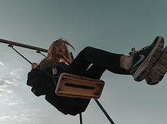 a woman is sitting on a swing with her feet in the air while holding onto an object