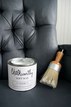 a black leather chair with a white paint can next to it and a wooden brush