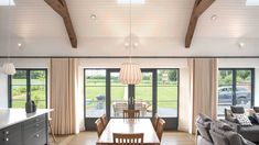 a living room filled with furniture next to a kitchen and dining room table in front of large windows