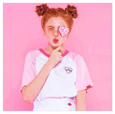 a girl holding a lollipop in front of her face and making a funny face