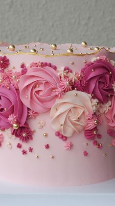 a pink and gold decorated cake with flowers on it