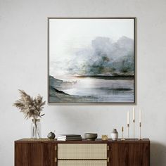 a painting hanging on the wall next to a sideboard with vases and candles