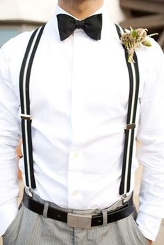 a man wearing a white shirt and black suspenders with a flower in his lapel