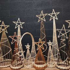 wicker christmas trees with star designs on them in front of a black brick wall