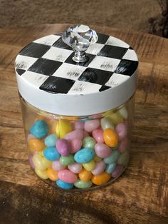 a jar filled with candy sitting on top of a wooden table next to a diamond