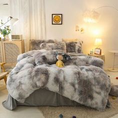 the bed is made with grey and white fur on it's comforter, along with two teddy bears