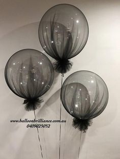 three clear balloons with black bows on them