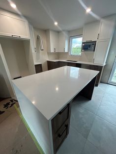 an empty kitchen with white counter tops and cabinets