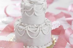 a three tiered white cake sitting on top of a table covered in pink confetti