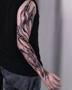 a man's arm covered in black ink with an intricate design on it,