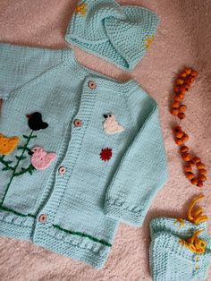 a knitted sweater, hat and booties are laying on the floor next to beads