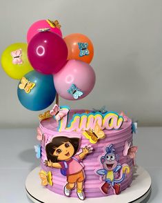 a birthday cake with an dora theme and balloons