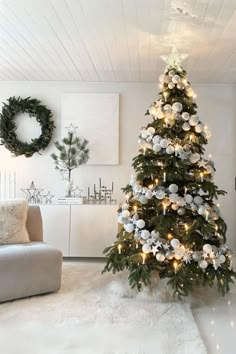 a decorated christmas tree in the corner of a living room with white and silver decorations