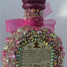 a bottle that has some kind of decoration on it's top and is decorated with beads