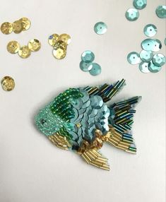 a fish made out of sequins sitting on top of a table next to buttons