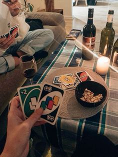 two people sitting on a couch holding cards and wine bottles in front of their faces