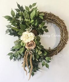 a wreath with flowers and greenery hanging on the wall