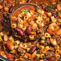 a ladle full of chili macaroni and cheese soup is being stirred with a spoon