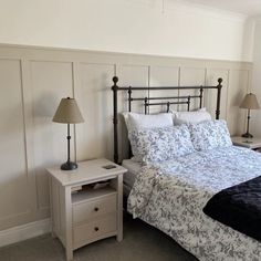 a bed sitting in a bedroom next to two lamps on either side of the bed