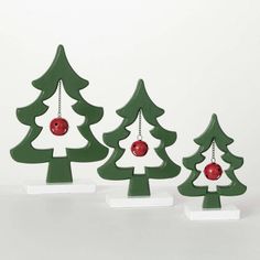 three wooden christmas trees with ornaments hanging from the top and one has a red ornament on it