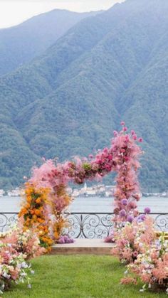 an outdoor ceremony set up with flowers and greenery in front of the water's edge