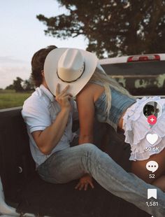 a man and woman sitting in the back of a pick up truck with their heads together